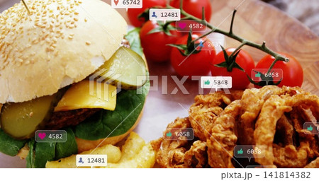 Showing sesame-bun burger sitting on wood board, with crinkle fries, onion rings, social icons Showing sesame-bun burger sitting on wood board, with crinkle fries, onion rings, social icons 141814382