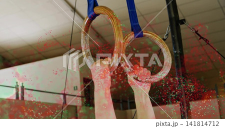 Gripping athlete's hands pulling on wood gymnastic rings at gym, with blue straps rigging and chalk Gripping athlete's hands pulling on wood gymnastic rings at gym, with blue straps rigging and chalk 141814712