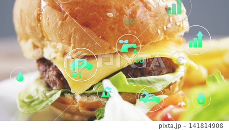 Showing sesame bun burger sitting on plate, showing melted cheese, lettuce, tomato, green icons Showing sesame bun burger sitting on plate, showing melted cheese, lettuce, tomato, green icons 141814908