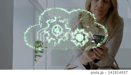 Holding smartphone, woman in blazer studying digital cloud with gears by tall windows, copy space Holding smartphone, woman in blazer studying digital cloud with gears by tall windows, copy space 141814937