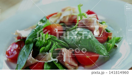 Displaying salad on white plate on tabletop featuring basil halved tomatoes greens ham oil HUD 141814960