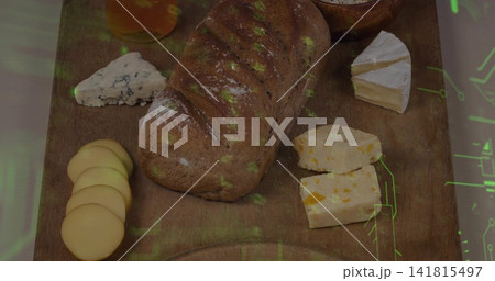 Showing artisan loaf centered on wood board with various cheeses, honey, green overlay 141815497