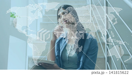 Sipping woman in denim shirt holding clear bottle and notebook on wooden stairs, world-map overlay 141815622