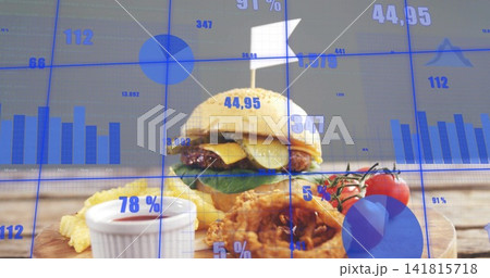 Displaying hamburger with fries and onion rings resting on wooden board, with blue data overlays 141815718