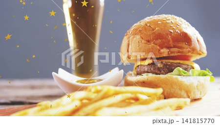 Showing sesame burger melting cheddar on board at studio, with fries, sauce, gold stars, copy space 141815770