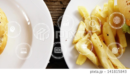 Displaying white plates with seasoned fries and burger buns, lettuce on dark table, digital icons Displaying white plates with seasoned fries and burger buns, lettuce on dark table, digital icons 141815843