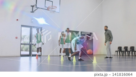 Dribbling player in green vest white shorts approaching yellow cones on gym orange ball, copy space Dribbling player in green vest white shorts approaching yellow cones on gym orange ball, copy space 141816064