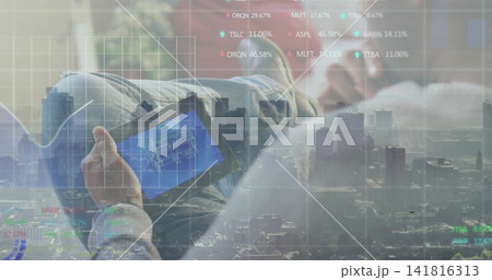 Reclining Asian man holding tablet viewing blueprint on couch in jeans with skyline tickers overlay Reclining Asian man holding tablet viewing blueprint on couch in jeans with skyline tickers overlay 141816313