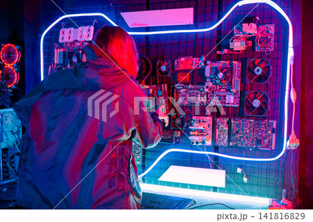Woman hacker. Asian woman wearing a black jacket working in manufacturing lab computing circuit for hacking programming system. Hacker works in a modern scientific Woman hacker. Asian woman wearing a black jacket working in manufacturing lab computing circuit for hacking programming system. Hacker works in a modern scientific 141816829