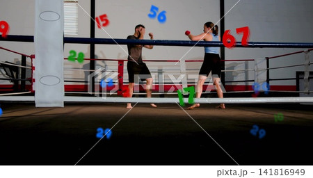 Sparring partners trading punches in boxing ring, light blue tank, red gloves, number overlays 141816949