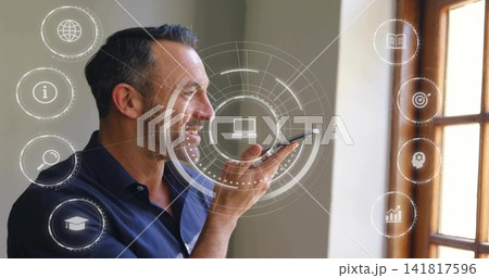 Speaking into smartphone, man in navy shirt controlling digital HUD by wooden-framed window at home Speaking into smartphone, man in navy shirt controlling digital HUD by wooden-framed window at home 141817596