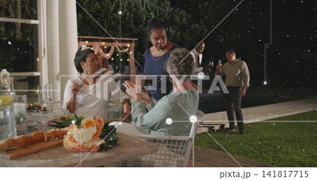 Chatting three women leaning at deck table, woman in dark blue dress, with floral centerpiece Chatting three women leaning at deck table, woman in dark blue dress, with floral centerpiece 141817715