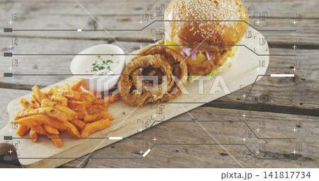 Displaying sesame-seed cheeseburger, onion rings, sweet-potato fries and ramekin on weathered board Displaying sesame-seed cheeseburger, onion rings, sweet-potato fries and ramekin on weathered board 141817734