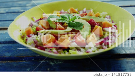 Showing yellow shallow bowl holding avocado greens salad on weathered blue table, overlay charts Showing yellow shallow bowl holding avocado greens salad on weathered blue table, overlay charts 141817755