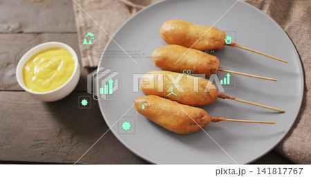 Displaying four corn dogs on skewers on gray plate at wooden table, with mustard and AR Displaying four corn dogs on skewers on gray plate at wooden table, with mustard and AR 141817767