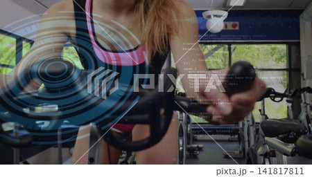 Leaning cyclist wearing black tank pink-trim shorts gripping spin bike holding knob in gym HUD over 141817811