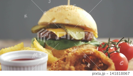 Displaying sesame-seed burger with beef-patty, cheddar, pickle-slices and lettuce on wooden board Displaying sesame-seed burger with beef-patty, cheddar, pickle-slices and lettuce on wooden board 141818067