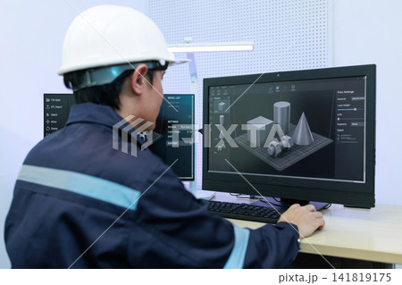 Engineer in hard hat using a computer with 3d modeling software in a modern office, working on industrial design and digital prototype. 141819175
