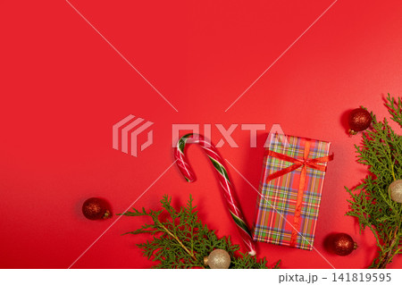Christmas gift candy cane branches and ornaments on red background Christmas gift candy cane branches and ornaments on red background 141819595