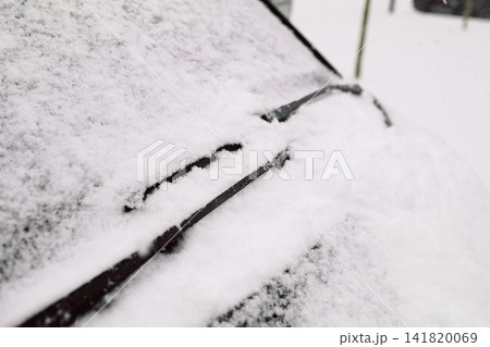 Car windshield covered in deep snow with raised wiper blade Car windshield covered in deep snow with raised wiper blade 141820069