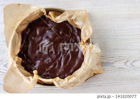 Top view of a whole freshly baked homemade chocolate brownie in a round springform pan lined with crumpled parchment paper. Copy space Top view of a whole freshly baked homemade chocolate brownie in a round springform pan lined with crumpled parchment paper. Copy space 141820077