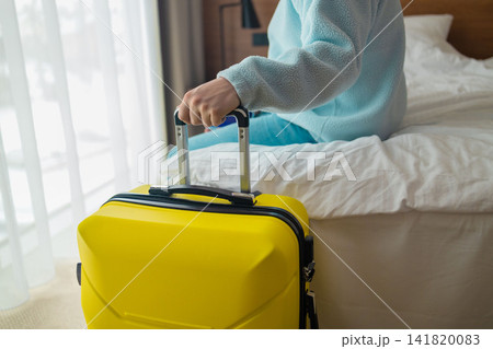 Man with yellow suitcase sitting on bed in hotel room Man with yellow suitcase sitting on bed in hotel room 141820083