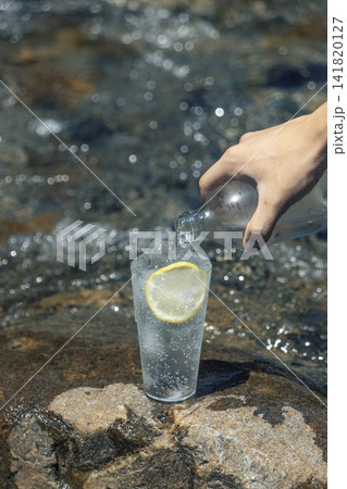 夏の清流でレモン入り炭酸水を注ぐ手元 夏の清流でレモン入り炭酸水を注ぐ手元 141820127