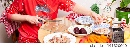 Woman is deboning herring at kitchen table to prepare traditional Christmas salad known as Herring Under Fur Coat, Ukrainian or Russian Christmas salad Shuba Woman is deboning herring at kitchen table to prepare traditional Christmas salad known as Herring Under Fur Coat, Ukrainian or Russian Christmas salad Shuba 141820640