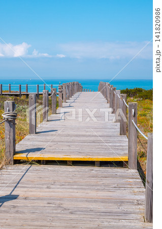 The wooden stairway at the rocky seashore on a sunny day. Polvoeira the beach. Pataias, Portugal, Europe The wooden stairway at the rocky seashore on a sunny day. Polvoeira the beach. Pataias, Portugal, Europe 141820986