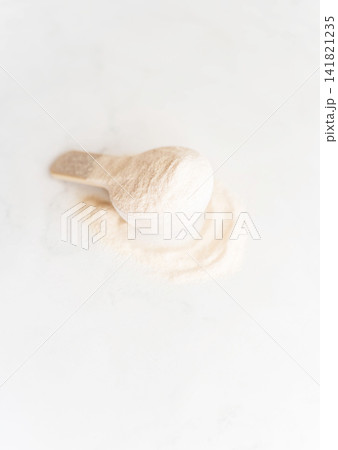 Scoop of white protein powder for sports nutrition on a light background. Scoop of white protein powder for sports nutrition on a light background. 141821235