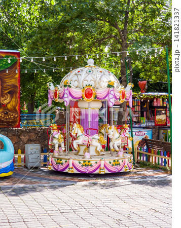 Children's carousel with horse figures in a park setting Children's carousel with horse figures in a park setting 141821337