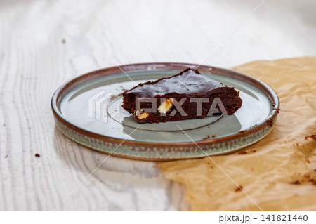 Side view of a triangular slice of homemade chocolate almond brownie served on a ceramic plate. Selective focus Side view of a triangular slice of homemade chocolate almond brownie served on a ceramic plate. Selective focus 141821440
