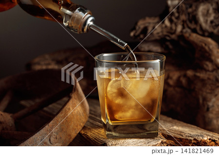Glass of whiskey with ice on a old wooden board. Glass of whiskey with ice on a old wooden board. 141821469