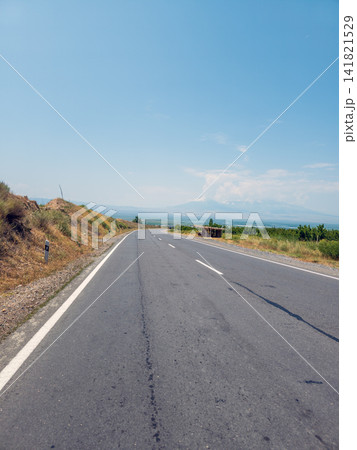 Empty highway winds through open countryside under cloudless sky 141821529