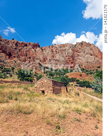 Desolate rural scene with crumbling stone cabin beside dry hillside Desolate rural scene with crumbling stone cabin beside dry hillside 141821570
