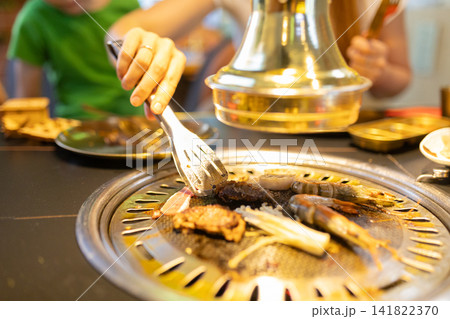 Family enjoying korean barbecue grilling meat and seafood 141822370