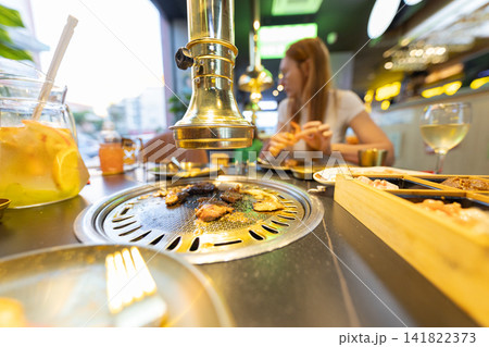Family enjoying korean barbecue in restaurant with grill Family enjoying korean barbecue in restaurant with grill 141822373