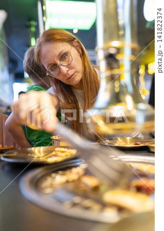 Woman grilling meat at korean barbecue restaurant dinner 141822374