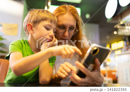 Mother and son using smartphone in restaurant Mother and son using smartphone in restaurant 141822393