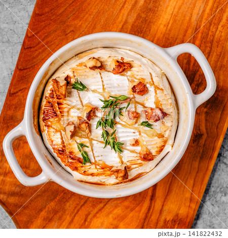 Baked cheese with honey and walnuts on a wooden board Baked cheese with honey and walnuts on a wooden board 141822432