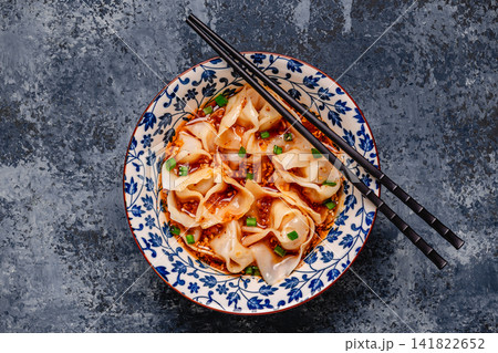 Wontons are placed in a bowl with spicy sauce. Wontons are placed in a bowl with spicy sauce. 141822652