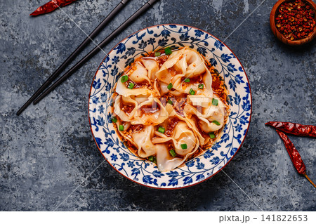 Wontons are placed in a bowl with spicy sauce. Wontons are placed in a bowl with spicy sauce. 141822653