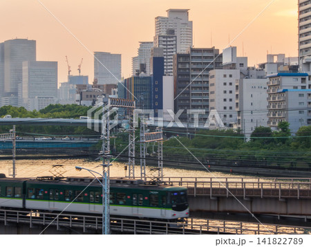 夕暮れを走る京阪電車と大阪のビル群 141822789