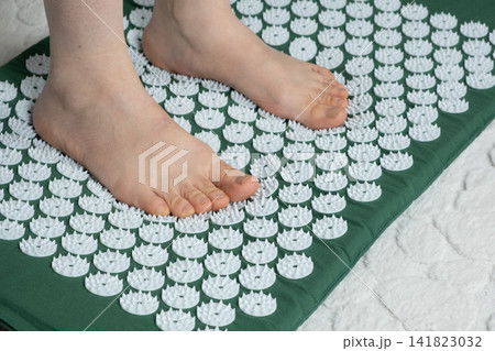Bare Feet Standing on Acupressure Mat for Foot Massage Therapy 141823032