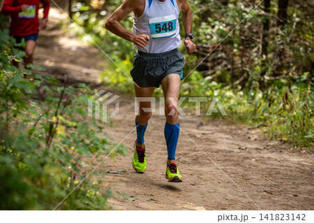 Male runner in compression sleeves running trail Male runner in compression sleeves running trail 141823142