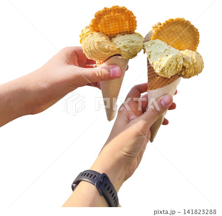 Two Hands Holding Pistachio and Caramel Gelato Ice Cream Cones with Waffles Isolated on a White Background Two Hands Holding Pistachio and Caramel Gelato Ice Cream Cones with Waffles Isolated on a White Background 141823288
