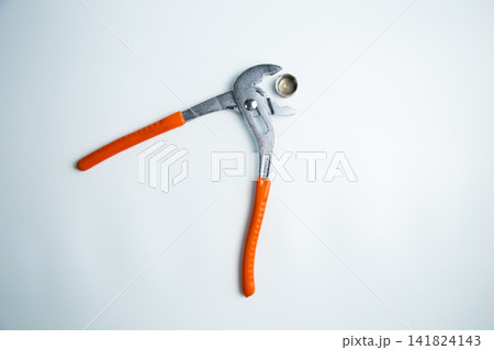 Close-up of the adjustable large wrench is open and between its teeth lies a pipe plug lying on a white background in the center. The concept of repair, plumbing, settings. High quality photo Close-up of the adjustable large wrench is open and between its teeth lies a pipe plug lying on a white background in the center. The concept of repair, plumbing, settings. High quality photo 141824143