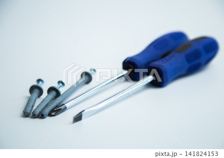 Close-up of two hands in work gloves holding screwdrivers against a white background. Concept of repair, handyman, tools, construction, installation. High quality photo 141824153