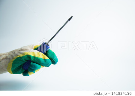 Close-up of a gloved hand holding a screwdriver on a white background. The concept of repair, twisting, handyman, construction, tools. High quality photo Close-up of a gloved hand holding a screwdriver on a white background. The concept of repair, twisting, handyman, construction, tools. High quality photo 141824156