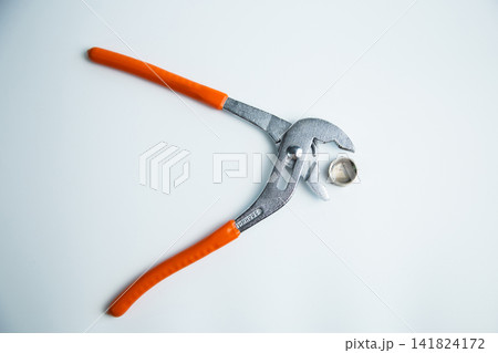 Close-up of the adjustable large wrench is open and between its teeth lies a pipe plug lying on a white background in the center. The concept of repair, plumbing, settings. High quality photo Close-up of the adjustable large wrench is open and between its teeth lies a pipe plug lying on a white background in the center. The concept of repair, plumbing, settings. High quality photo 141824172